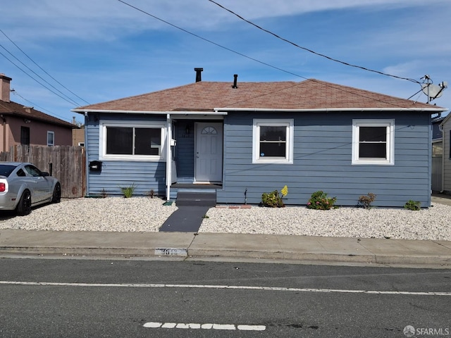 bungalow featuring roof with shingles and fence