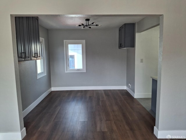 unfurnished dining area featuring dark wood-style floors and baseboards