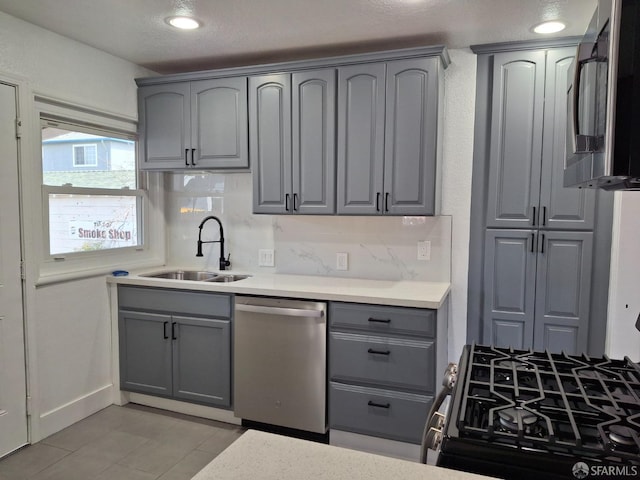 kitchen with a sink, stainless steel appliances, gray cabinetry, and decorative backsplash