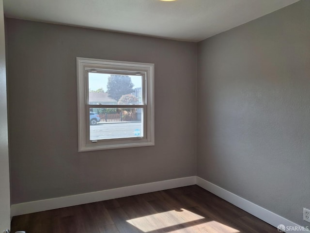 empty room featuring dark wood-style floors and baseboards