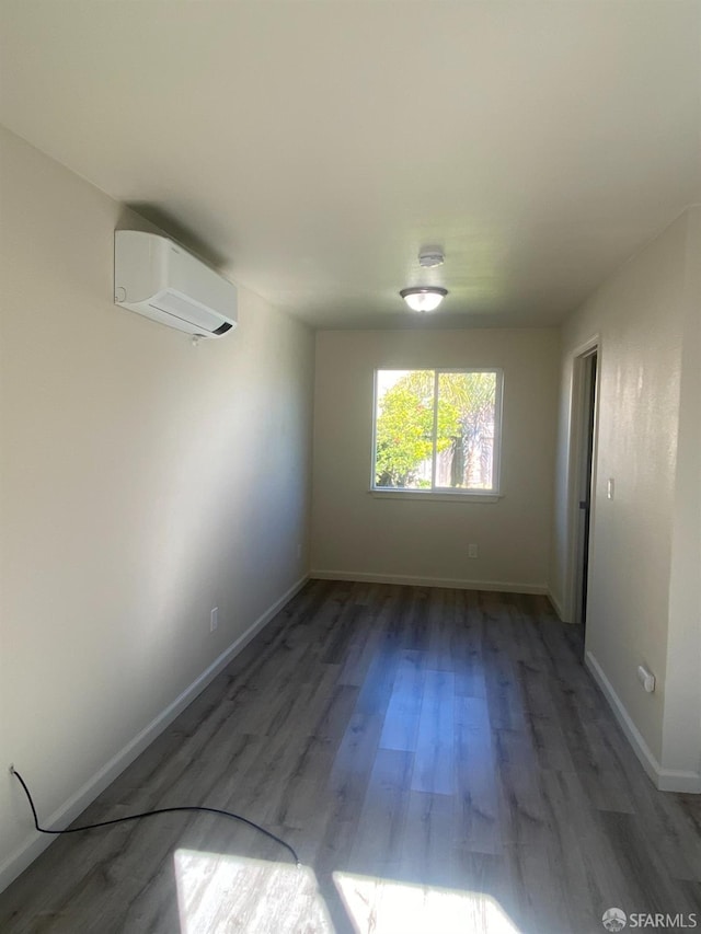 empty room featuring baseboards, wood finished floors, and a wall unit AC