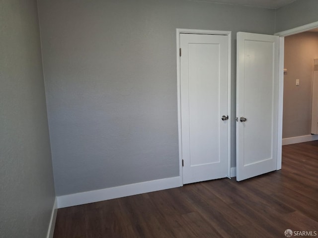 unfurnished bedroom with dark wood-type flooring and baseboards