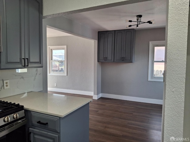 kitchen with gray cabinetry, dark wood-style flooring, a wealth of natural light, and stainless steel gas range oven