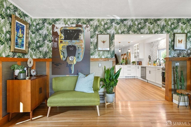 sitting room featuring crown molding, light wood-style floors, and wallpapered walls