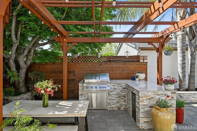 view of patio with area for grilling, exterior kitchen, fence, and a pergola