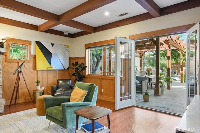 sitting room with beamed ceiling, wainscoting, wood finished floors, and visible vents
