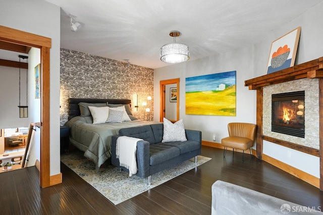 bedroom with baseboards, a glass covered fireplace, and wood finished floors