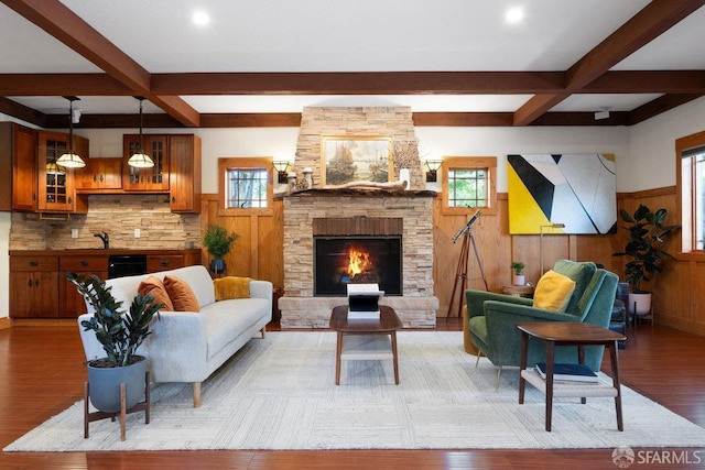 living area with a fireplace, wainscoting, light wood finished floors, and beam ceiling