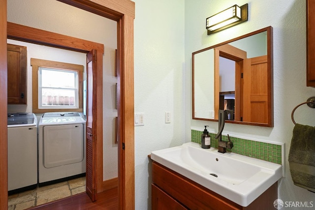 bathroom featuring a textured wall, tasteful backsplash, washer and clothes dryer, and vanity