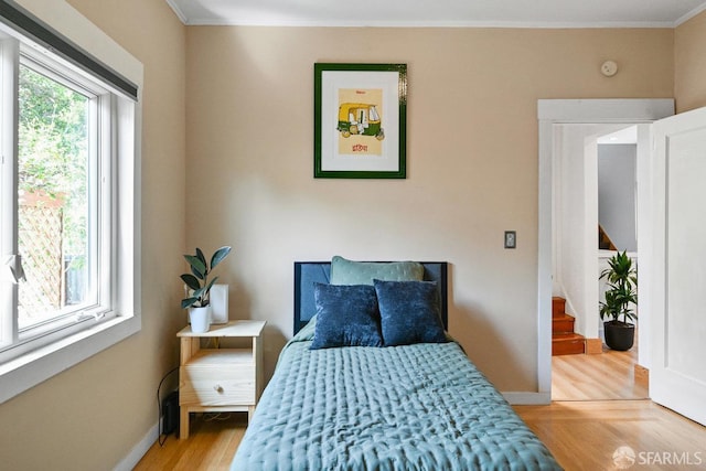 bedroom featuring crown molding, baseboards, and light wood-style flooring