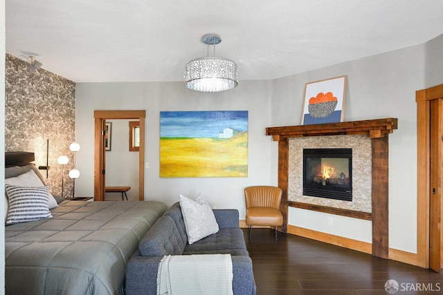 bedroom with a glass covered fireplace, an inviting chandelier, and wood finished floors