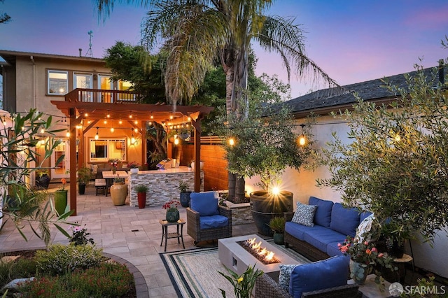 view of patio / terrace featuring fence, a balcony, and an outdoor living space with a fire pit