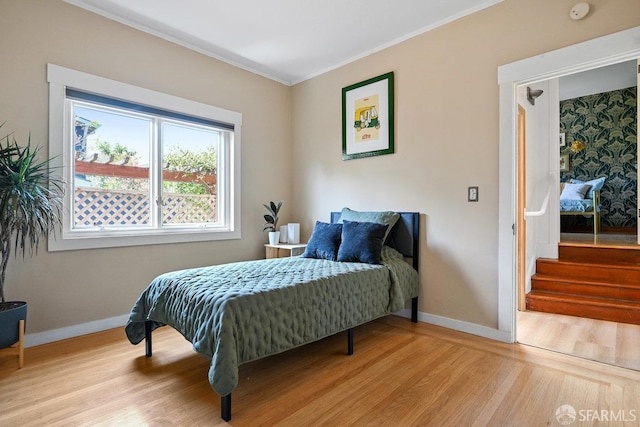bedroom featuring baseboards, ornamental molding, and wood finished floors