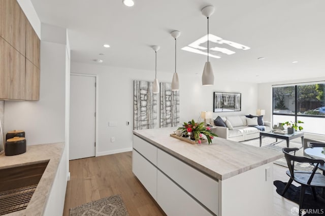 kitchen with a center island, light hardwood / wood-style flooring, white cabinets, and pendant lighting