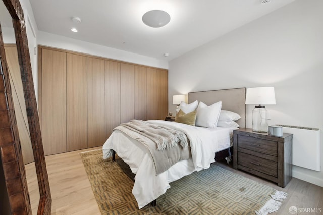 bedroom with radiator and light hardwood / wood-style flooring