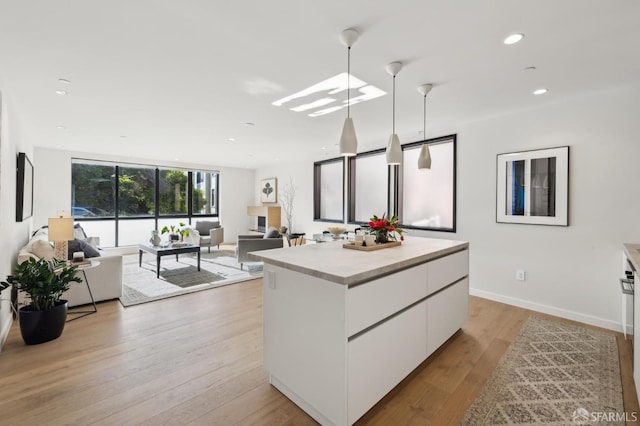 kitchen featuring white cabinets, a kitchen island, light wood-type flooring, and hanging light fixtures