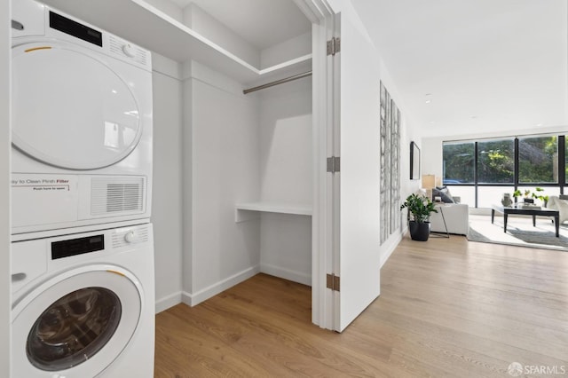 washroom with stacked washer and dryer and light hardwood / wood-style floors