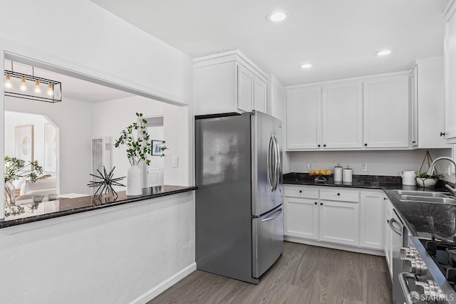 kitchen featuring sink, dark stone countertops, appliances with stainless steel finishes, dark hardwood / wood-style floors, and white cabinets