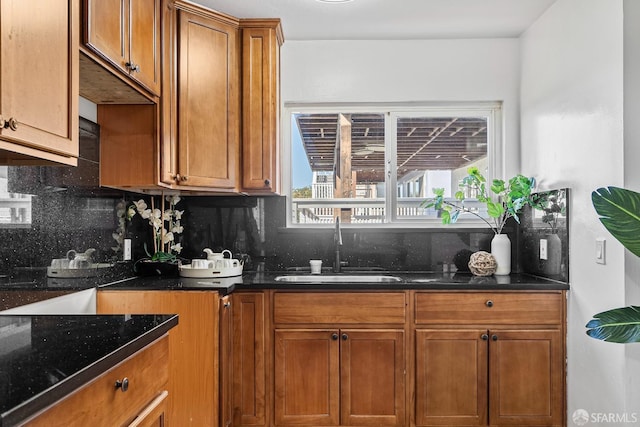 kitchen with sink, decorative backsplash, dark stone counters, and a healthy amount of sunlight