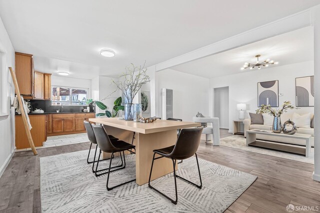 kitchen with sink, a center island, a notable chandelier, light hardwood / wood-style floors, and a kitchen bar