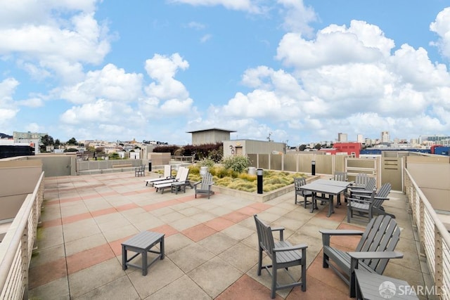 view of patio / terrace featuring outdoor dining space, fence, and a city view