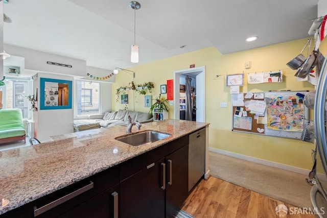 kitchen with light wood-style flooring, open floor plan, decorative light fixtures, a sink, and stainless steel dishwasher