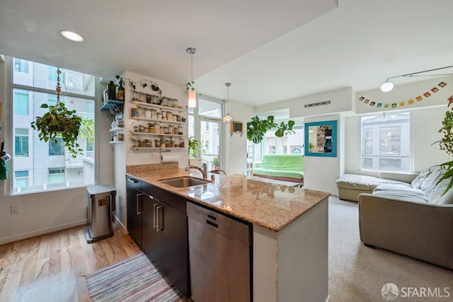 kitchen with pendant lighting, open shelves, open floor plan, a sink, and dishwasher