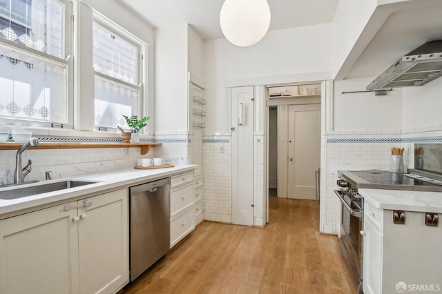 3011 Van Ness Ave, San Francisco, CA 94109 - kitchen with appliances with stainless steel finishes, a sink, light wood-style flooring, tasteful backsplash, and tile walls