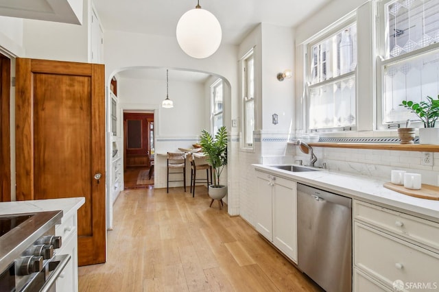 3011 Van Ness Ave, San Francisco, CA 94109 - kitchen featuring appliances with stainless steel finishes, arched walkways, a sink, light wood-style flooring, and decorative light fixtures