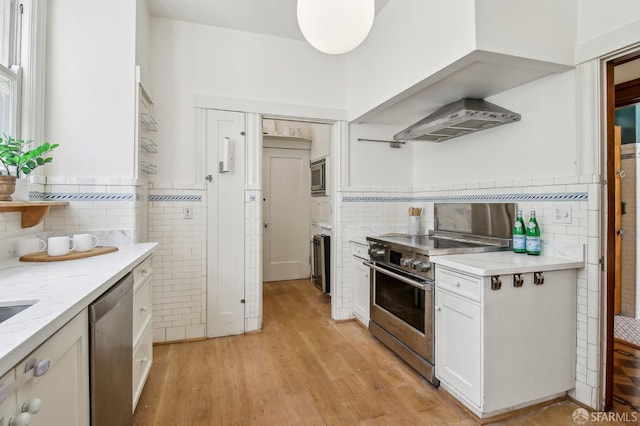 3011 Van Ness Ave, San Francisco, CA 94109 - kitchen with tile walls, stainless steel appliances, ventilation hood, white cabinetry, and light wood-style floors