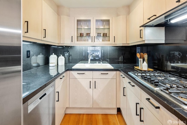 1340 Clay St Unit 302, San Francisco, CA 94109 - kitchen featuring stainless steel appliances, under cabinet range hood, tasteful backsplash, glass insert cabinets, and dark countertops