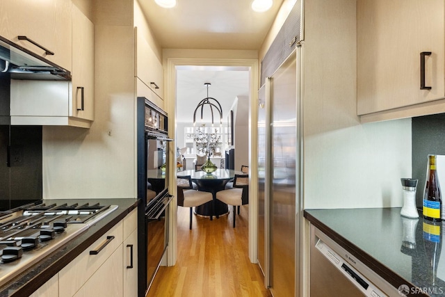 1340 Clay St Unit 302, San Francisco, CA 94109 - kitchen featuring dark countertops, appliances with stainless steel finishes, light wood-style floors, a chandelier, and ventilation hood