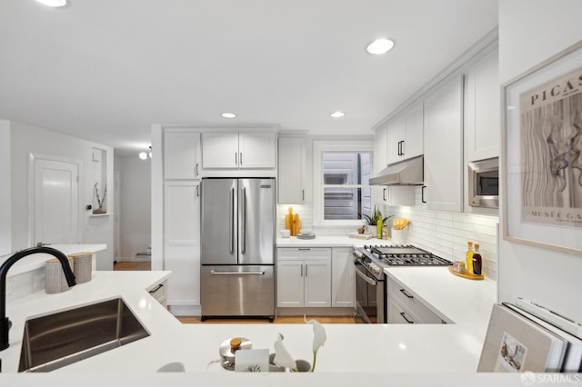 kitchen with tasteful backsplash, stainless steel appliances, sink, and white cabinets