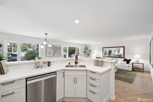 kitchen with light parquet floors, sink, stainless steel dishwasher, and white cabinets