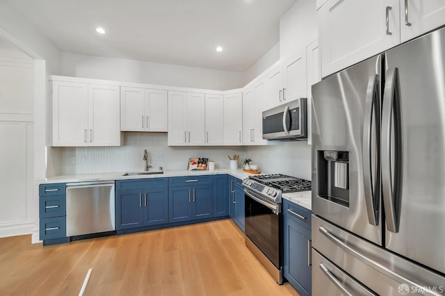 291 Church St, San Francisco, CA 94114 - kitchen featuring stainless steel appliances, blue cabinetry, light countertops, light wood finished floors, and white cabinets