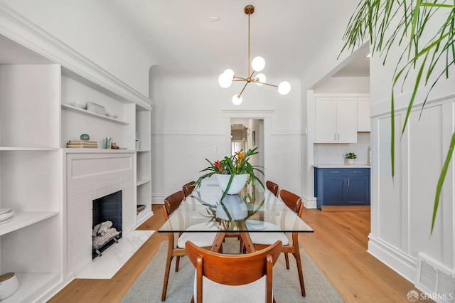 291 Church St, San Francisco, CA 94114 - dining area with light wood-type flooring, a fireplace with flush hearth, a chandelier, and wainscoting