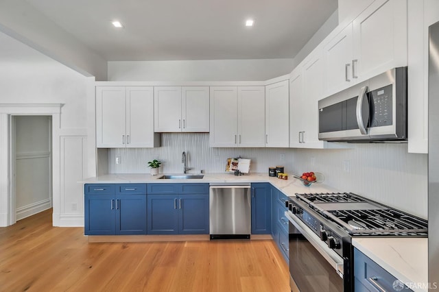 291 Church St, San Francisco, CA 94114 - kitchen featuring appliances with stainless steel finishes, blue cabinets, light wood finished floors, white cabinets, and backsplash