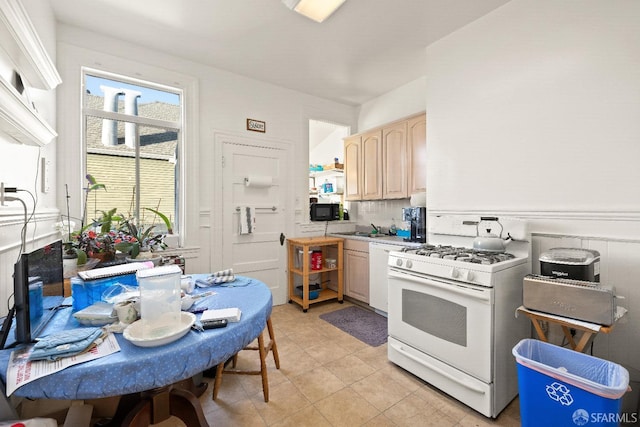 kitchen featuring light brown cabinetry, sink, dishwashing machine, light tile patterned floors, and white gas stove