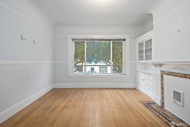 unfurnished living room featuring heating unit and light hardwood / wood-style flooring