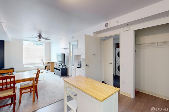 interior space with white cabinets, ceiling fan, wood-type flooring, and stacked washing maching and dryer