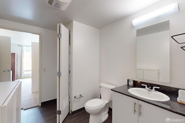 bathroom featuring toilet, vanity, and wood-type flooring