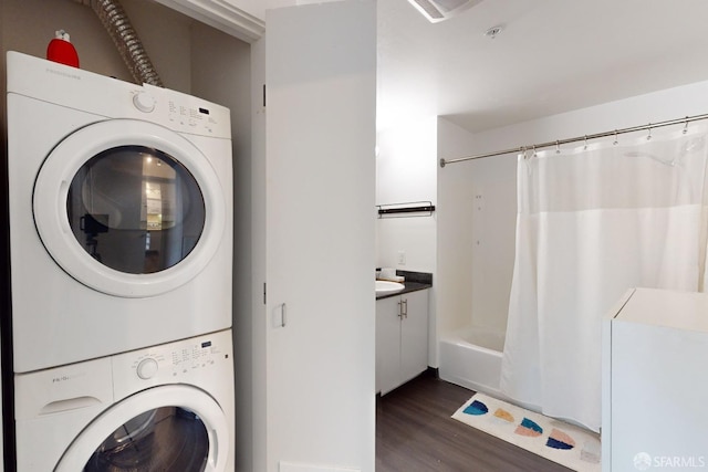 clothes washing area featuring dark hardwood / wood-style floors and stacked washer and dryer