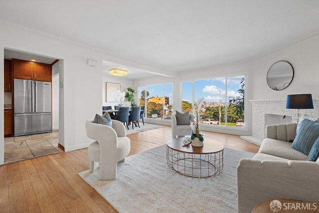 living area with a fireplace, light wood-style flooring, and baseboards