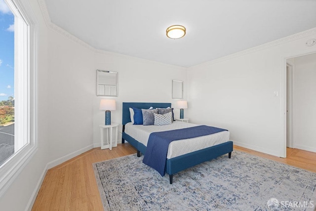 bedroom featuring baseboards, wood finished floors, and ornamental molding