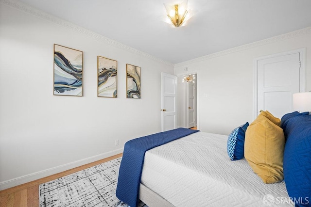 bedroom featuring baseboards, wood finished floors, and ornamental molding