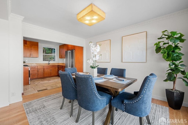 dining space featuring ornamental molding, light wood-style flooring, and baseboards