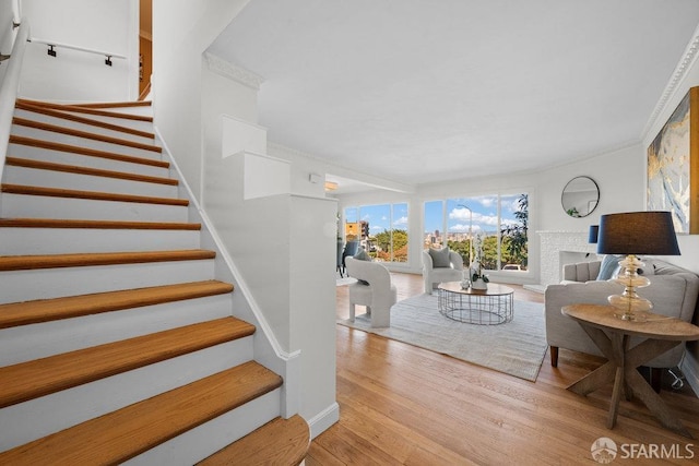 stairs with ornamental molding, a fireplace, and wood finished floors