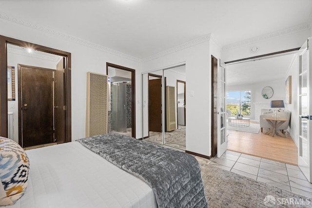 bedroom with light tile patterned floors, baseboards, ensuite bath, crown molding, and a closet