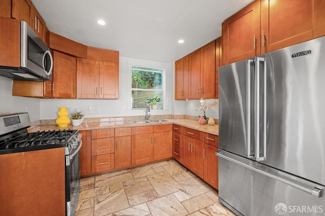 kitchen featuring stone tile floors, brown cabinets, stainless steel appliances, a sink, and recessed lighting