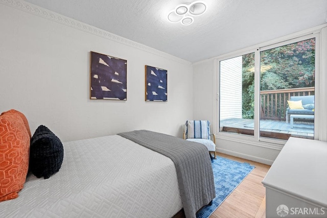 bedroom with a textured ceiling, light wood finished floors, and baseboards